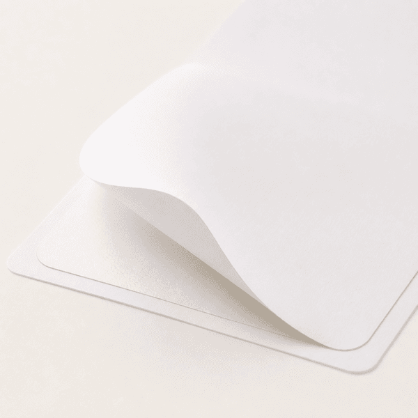 Close-up of white vinyl label stock lifting from its liner